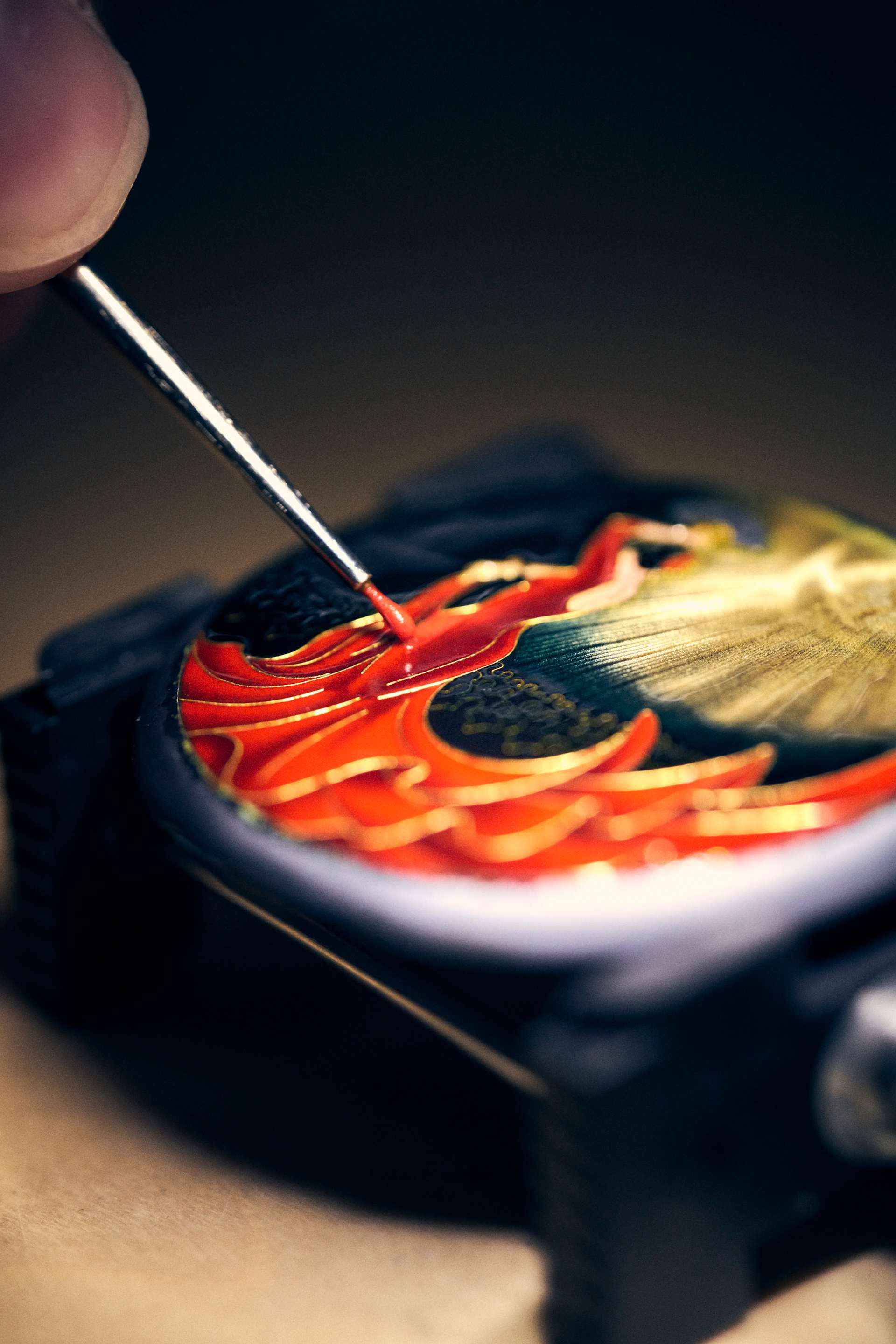 An enameller applies enamel to a dial with a brush
